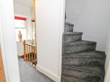 A carpeted staircase and hallway with a window and a vase on the windowsill at Ty Gwynn in Tanygrisiau