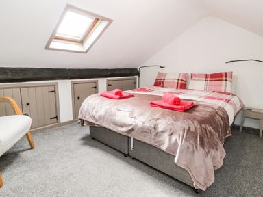 A bedroom with a double bed under a skylight and small storage doors on one wall at Ty Gwynn in Tanygrisiau