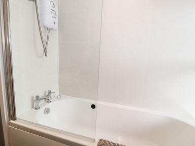 A bathroom with a bathtub and a mounted shower at Ty Gwynn in Tanygrisiau
