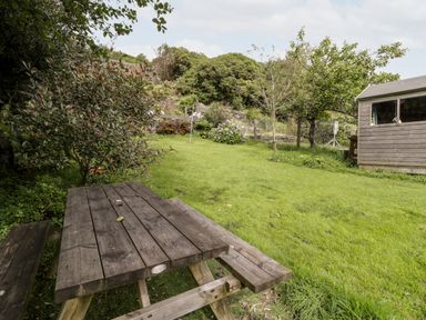 A garden with a wooden picnic table a shed and trees at Ty Gwynn in Tanygrisiau