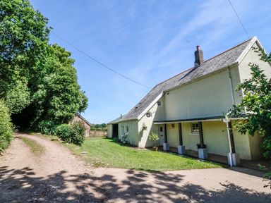 A rural house with a driveway and trees surrounding the property at Marsh Cottage in North Molton