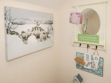 A corner with a wall mirror, decorative signs, and a large canvas print of sheep at The Store Rooms in Whitby