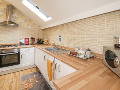 A kitchen with wooden countertops white cabinets a stainless steel oven and sink at The Store Rooms in Whitby