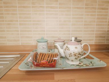 A kitchen counter with a tray holding a teapot, tea biscuits, and labeled canisters for tea, coffee, and sugar at The Store Rooms in Whitby