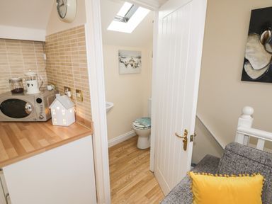A small kitchen corner with a microwave and decorative items next to a bathroom with a toilet and skylight at The Store Rooms in Whitby