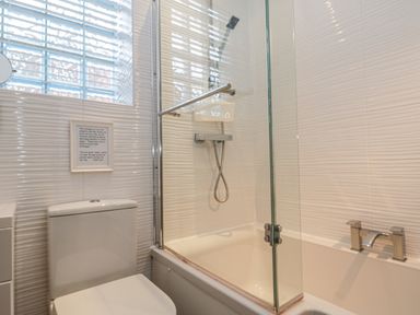 A bathroom with a toilet and a bathtub with a shower at The Store Rooms in Whitby
