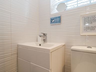 A bathroom sink with a faucet and a toilet next to it at The Store Rooms in Whitby