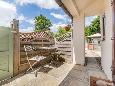 A small outdoor patio with a table and two chairs next to a wooden fence at Willow Cottage in Ulrome near Skipsea