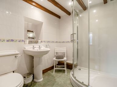 A bathroom with a toilet sink shower and a chair with towels at Willow Cottage in Ulrome near Skipsea