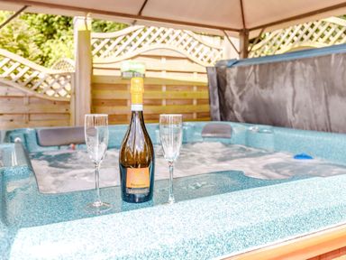 A hot tub with a bottle of prosecco and two empty glasses at Willow Cottage in Ulrome near Skipsea