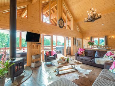 A wooden living room with a fireplace a leather sofa armchair coffee table and dining table at Hampton Lodge in Ellesmere