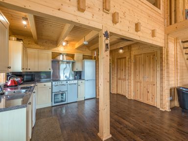 A kitchen with wooden cabinets and stainless steel appliances next to wooden doors and staircase at Hampton Lodge in Ellesmere