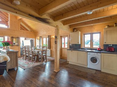 A wooden kitchen and dining area with a dining table and chairs next to a window at Hampton Lodge in Ellesmere