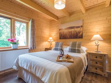 A bedroom with a bed and wooden furniture and walls at Hampton Lodge in Ellesmere