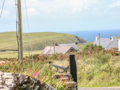 A rural landscape with hills houses and ocean in the background at An Nead in Ballinknockane near Dingle County Kerry