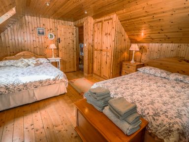 A bedroom with two beds bedside tables lamps and wooden walls at An Nead Ballinknockane near Dingle County Kerry