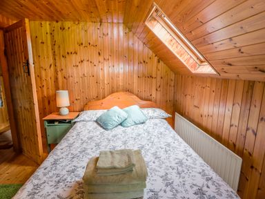 A bedroom with a bed two pillows a bedside table with a lamp and folded towels on the bed at An Nead Ballinknockane near Dingle County Kerry