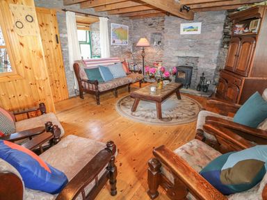 A living room with wooden furniture stone walls and a fireplace at An Nead in Ballinknockane near Dingle County Kerry