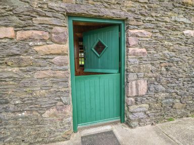 A green half door with the top half open and a stone wall surrounding it at An Nead in Ballinknockane near Dingle County Kerry
