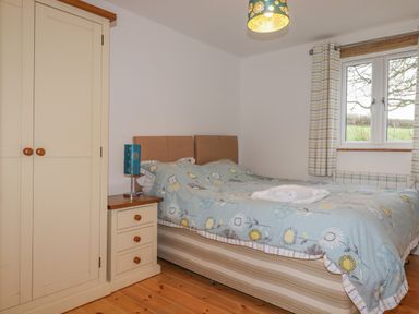 A bedroom with a double bed bedside table wardrobe and window at Vine Cottage in St Ewe near Sticker 