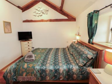 A bedroom with a bed, television, and dresser at Sonya's Cottage Anthorn, Solway Firth