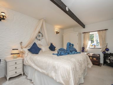 A bedroom with a bed and window at Poldark Cottage East Taphouse