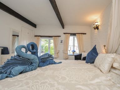 A bedroom with towels arranged in swan shapes at Poldark Cottage East Taphouse