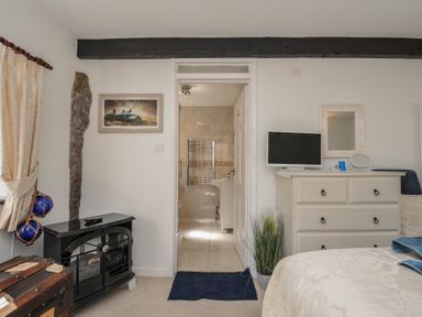 A bedroom with a bed and a bathroom entrance at Poldark Cottage in East Taphouse