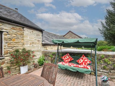 An outdoor area with a swing seat and a table at Poldark Cottage in East Taphouse