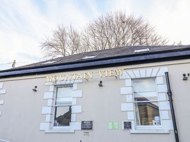 Exterior of a building with two windows and gold letters spelling mountain view at Mountain View in Penmaenmawr
