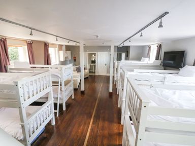 A dormitory room with multiple white bunk beds and a television at Mountain View in Penmaenmawr
