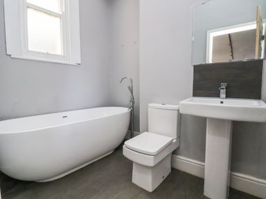 A bathroom with a freestanding bathtub toilet and pedestal sink at Mountain View in Penmaenmawr