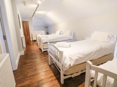 A dormitory room with single beds and white linens at Mountain View in Penmaenmawr