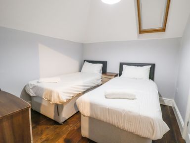 A bedroom with two single beds a nightstand wooden flooring and a skylight window at Mountain View in Penmaenmawr