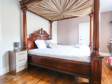 A bedroom with a wooden four-poster bed and bedside table with a lamp at Mountain View in Penmaenmawr
