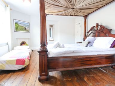 A bedroom with a four-poster wooden bed and a single bed beside a window at Mountain View in Penmaenmawr