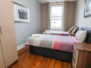 A bedroom with two single beds on a wooden floor and a window at Mountain View in Penmaenmawr