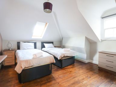 A bedroom with two single beds bedside tables a window and a skylight at Mountain View in Penmaenmawr