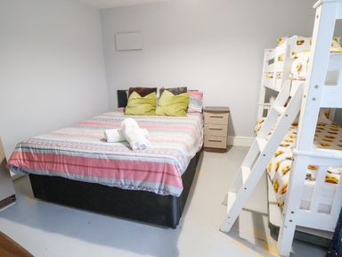 A bedroom with a double bed pillows towel and a bunk bed with emoji bedding at Mountain View in Penmaenmawr