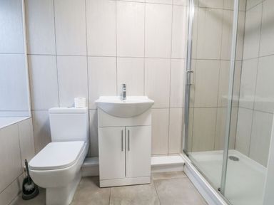 A bathroom with a toilet a sink cabinet and a glass shower enclosure at Mountain View in Penmaenmawr