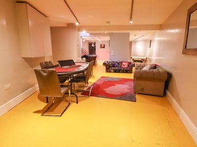 A game room with a poker table and chairs a multicolored sofa a beige sofa a red patterned rug and a pool table at Mountain View in Penmaenmawr