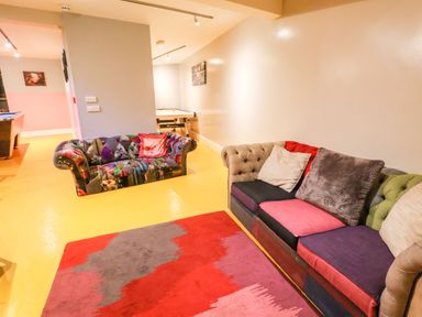 A room with two colorful sofas a red and gray rug and an air hockey table at Mountain View in Penmaenmawr