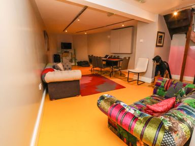 A living room with two sofas a dining table with chairs a white chair and a sculpture of a dog at Mountain View in Penmaenmawr