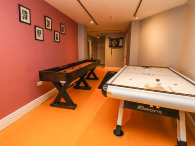 A game room with an air hockey table a shuffleboard table and a dartboard on the wall at Mountain View in Penmaenmawr