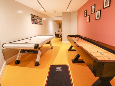 A game room with an air hockey table and a shuffleboard table with framed photos on the walls at Mountain View in Penmaenmawr