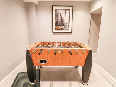 A foosball table in a room with gray walls and a framed black and white photo with a yellow taxi at Mountain View in Penmaenmawr