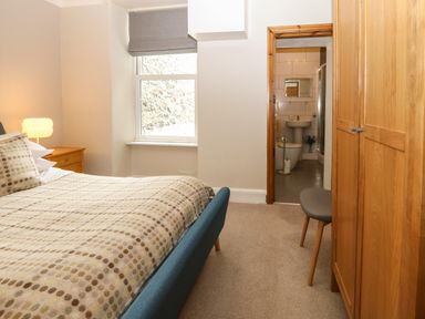 A bedroom with a bed chair wardrobe and an ensuite bathroom at Y Castell Apartment 2 in Criccieth