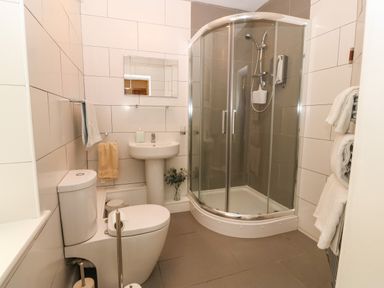 A bathroom with a toilet sink shower and towels on a rack at Y Castell Apartment 2 in Criccieth
