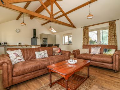 A living room with brown sofas and a wooden coffee table in an open kitchen area at Sunnyside Cottage in Blackborough End near Kings Lynn