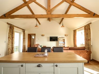 A living area with wooden ceiling beams a wooden countertop and brown sofas at Sunnyside Cottage in Blackborough End near Kings Lynn
